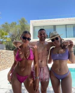 Three people in swimwear posing by a pool.