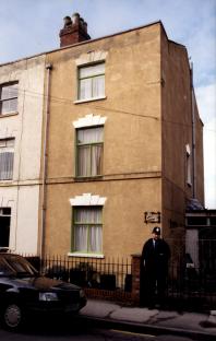 Photo of 25 Cromwell Street, the home of Fred and Rose West, with a police officer standing outside.