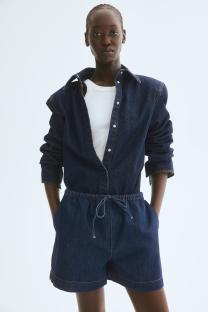 Model wearing denim drawstring shorts and a denim shirt.
