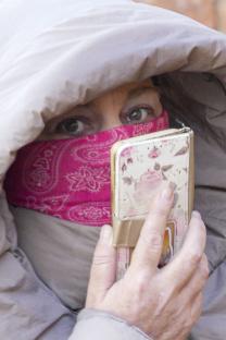 Karen Matthews leaving her home, partially obscured by a hooded coat and a pink bandana.
