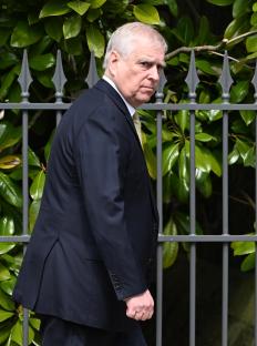 Prince Andrew walking near a fence.