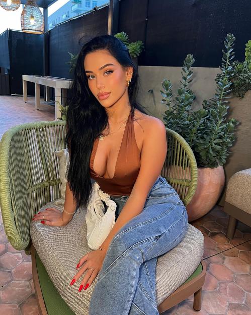 Woman with long dark hair sitting on a chair.
