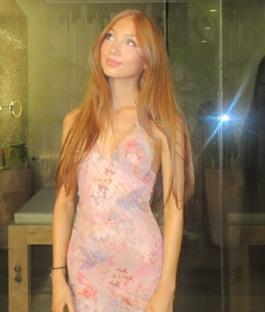 Woman in pink dress in front of a glass wall.