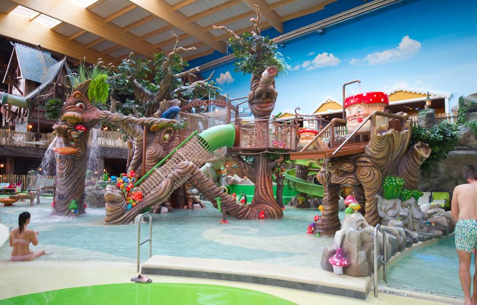 Children's water play area with whimsical tree and mushroom sculptures.