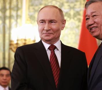Vladimir Putin and To Lam shaking hands.