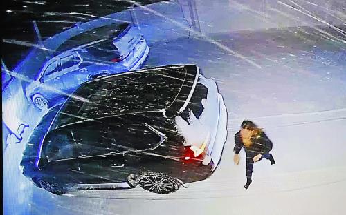 Security camera footage of a woman approaching a dark-colored SUV in snowy conditions.