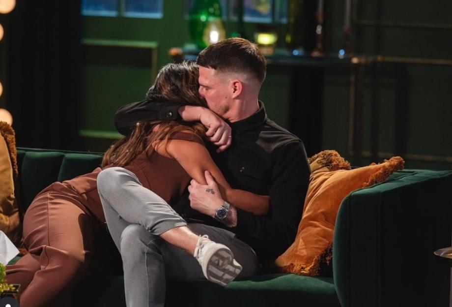 A couple embracing each other while sitting on a green couch.