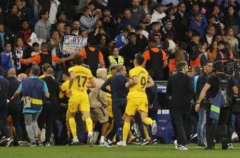 FC Barcelona players running off the field after a match, surrounded by fans and security.