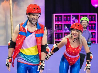 Two people wearing roller skating outfits and helmets.