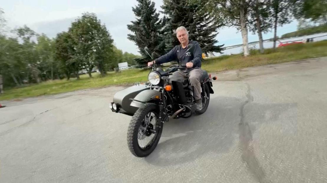 Man riding a Ural motorcycle with a sidecar.