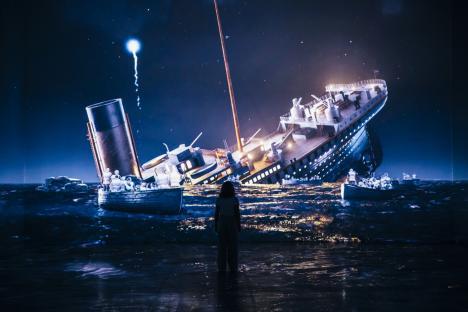 A person stands before a large projection of the Titanic sinking.