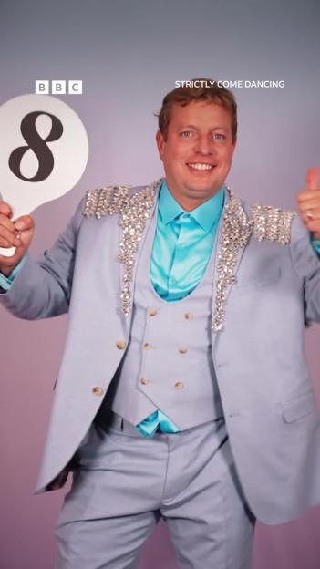 Thomas Skinner from Strictly Come Dancing holding up a paddle with the number 8.