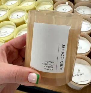 Hand holding an iced coffee-scented candle in a Tesco store.