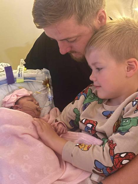Father and son comforting newborn baby in hospital.