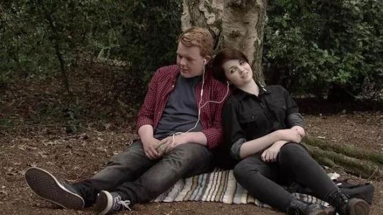 Craig Tinker and Caitlin Ryan from Coronation Street sitting together in a wooded area.
