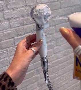 A shower head covered in cleaning foam.