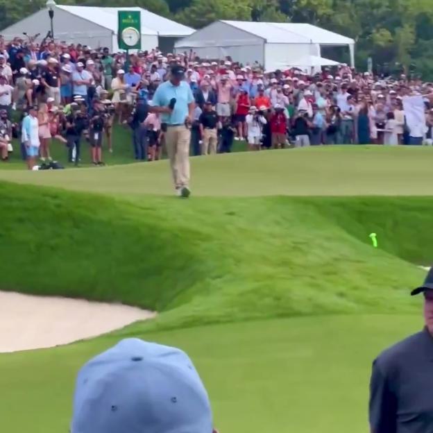 Golfer walking on the 18th green during a PGA FedEx Cup event.