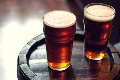 Two pints of bitter ale on a wooden barrel.