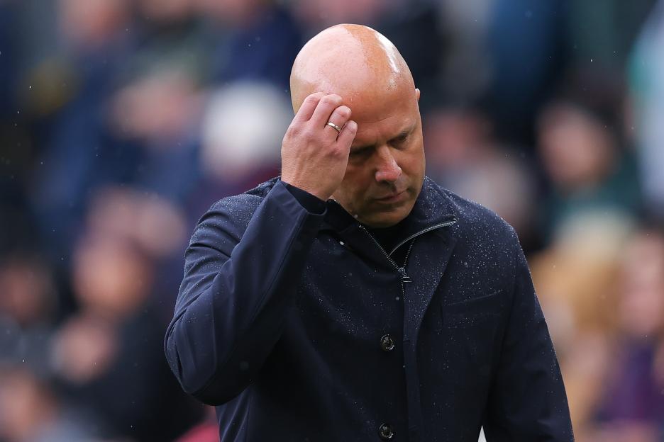 Liverpool head coach Arne Slot looks dejected, touching his head with one hand.
