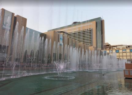 Blue illuminated fountains at night in front of a building.