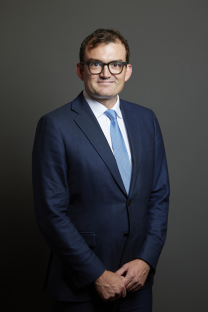 Portrait of a man in a suit and glasses.