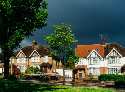 Two houses on a residential street under a dark sky.