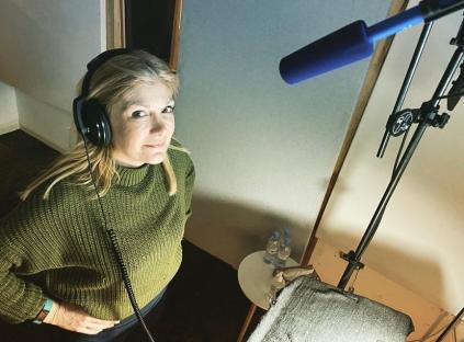 Woman in recording studio wearing headphones.