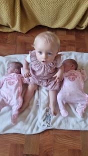A toddler sitting between two newborn twins.