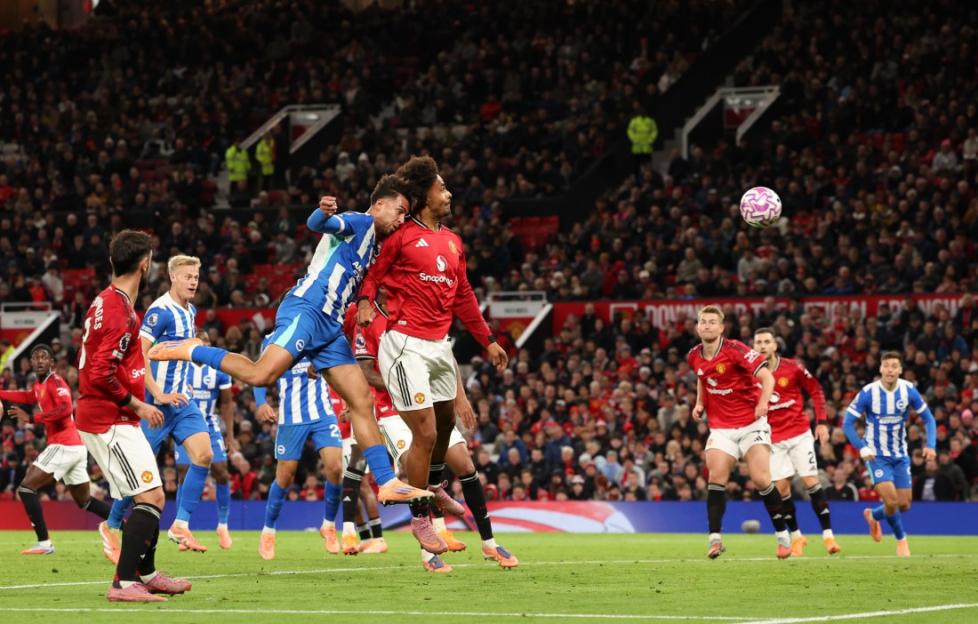 Manchester United and Brighton players vie for a header during a Premier League match.