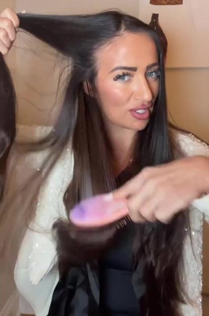 Chantelle Houghton brushing her long, dark hair with a pink and purple brush.