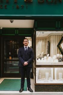 Man in suit standing outside jewelry store.