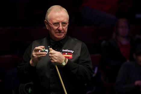 Dennis Taylor chalking his cue at a snooker match.