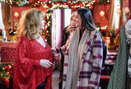 Three women conversing in a festively decorated pub.