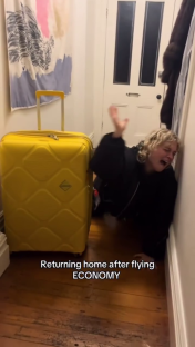 Woman dramatically leaning against a wall after arriving home from an economy flight.