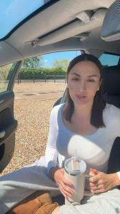 Liana Isadora Van Riel in a car, holding a drink.