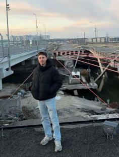 Man standing near a damaged bridge in Kyiv, Ukraine.