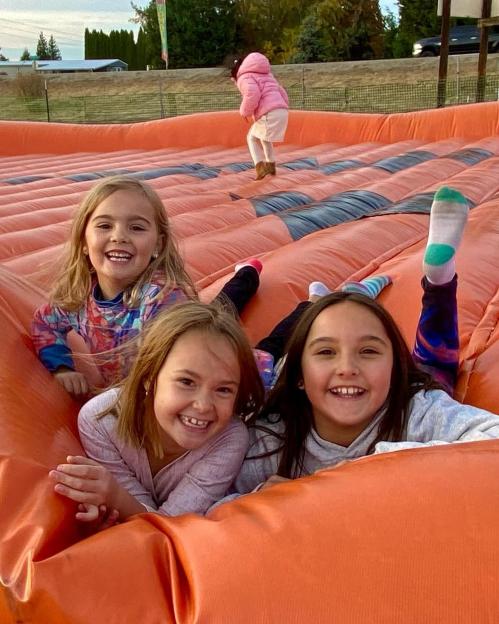 Three girls playing on a large inflatable.