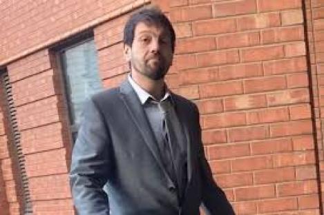 Man in suit outside brick building.