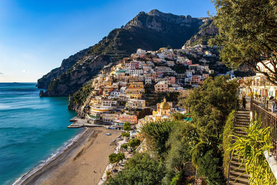 Aerial view of Positano, Italy, showing colorful buildings on a hillside overlooking the sea.