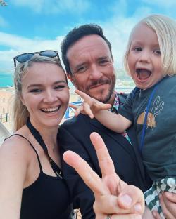 Selfie of a family of three, making peace signs.