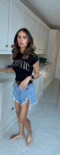 Woman in denim shorts and a black t-shirt walking through a kitchen.