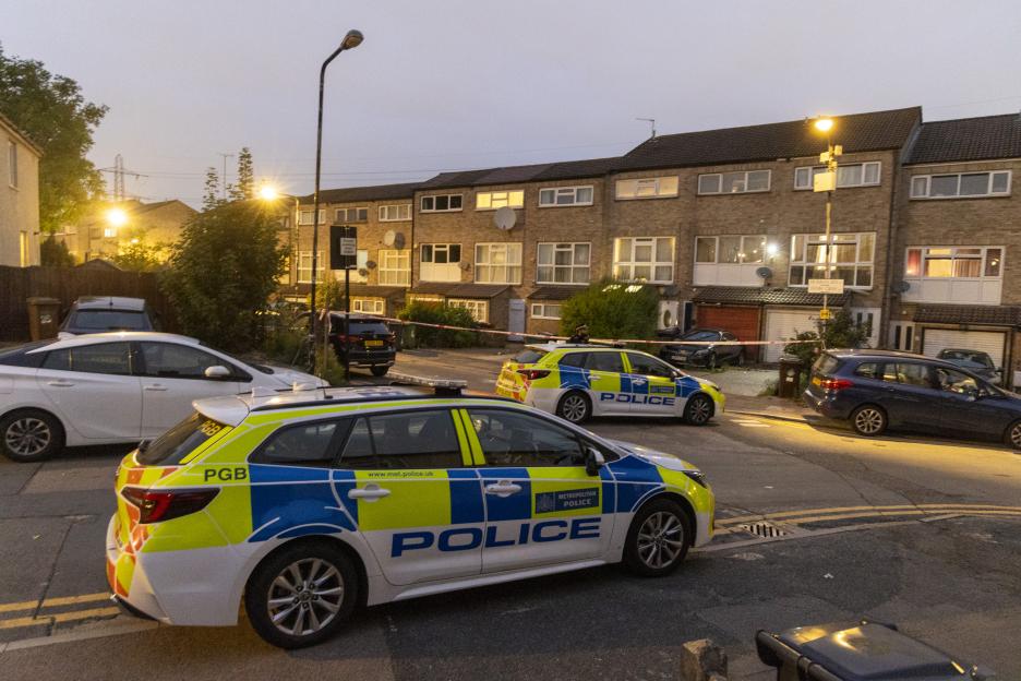 Police cars and crime scene tape outside residential buildings.
