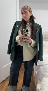 Woman in a green blazer and jeans taking a selfie.