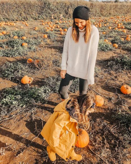 A woman and a young child in a pumpkin patch.