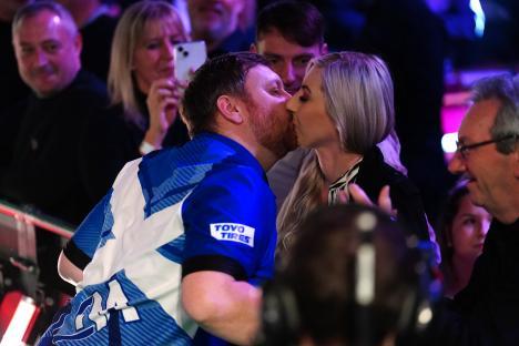 Fallon Sherrock and Cameron Menzies embracing and kissing at a darts championship.
