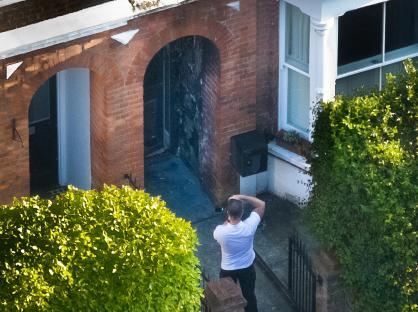 Photographer taking pictures of fire-damaged house entrance.