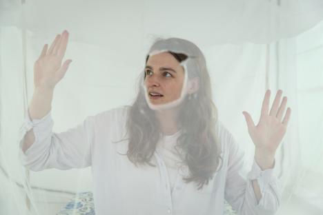 Woman in white shirt inside a bed net.