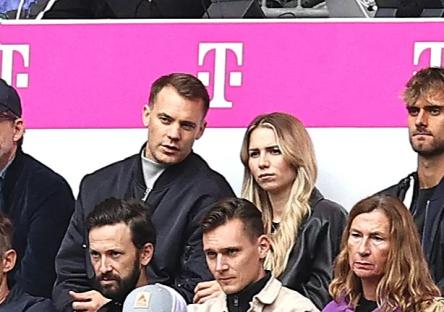 Manuel Neuer and his girlfriend in the stands at a soccer match.
