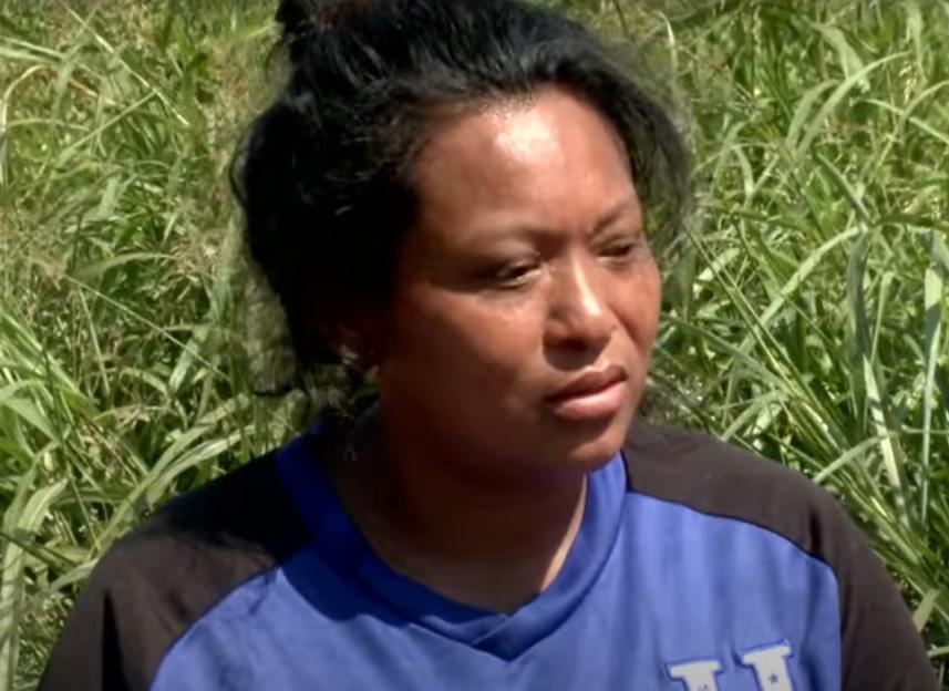 Woman in blue shirt looks thoughtfully toward the camera.