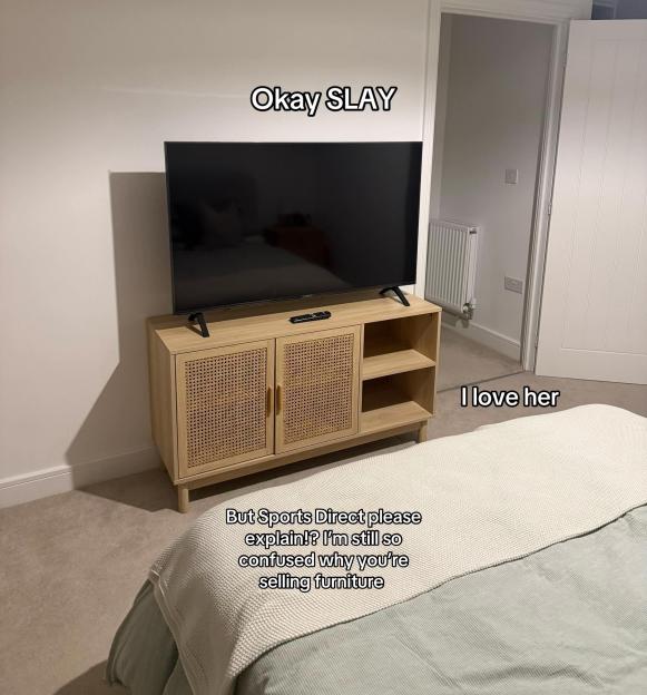 A flat-screen TV on a light wood media console with woven cane cabinet doors and open shelves.